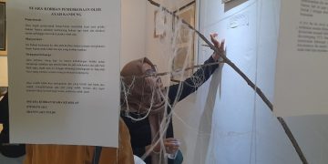 Para pengunjung melihat satu per satu karya korban kekerasan di gedung Teater Arena Taman Budaya Provinsi Jambi, Jumat sore (16/12). [Dok Hajrin Febrianto]