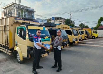 Pihak Kepolisian Resor Kota Jambi menunjukkan surat tilang di depan lima mobil angkutan batu bara yang melanggar. [Foto Aurduri.com/Reza]