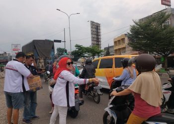 Ketua DPC HBB Kota Jambi, Ika Saragih sedang membagikan takjil bagi pengendara di Simpang Rimbo, Rabu (12/4/23). [Dok. Charles]
