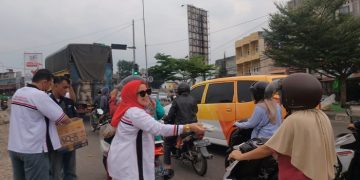 Ketua DPC HBB Kota Jambi, Ika Saragih sedang membagikan takjil bagi pengendara di Simpang Rimbo, Rabu (12/4/23). [Dok. Charles]