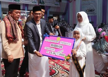 Gubernur Al Haris saat memberikan hadiah umroh gratis kepada 2 orang guru dan 3 siswa SIT Nurul ‘Ilmi Jambi pada Wisuda Akbar Tahfidz Al-Qur’an Ke-XIII SIT Nurul ‘Ilmi Jambi di GOR Kota Baru Jambi, Sabtu (24/02/2024). [Foto: Diskominfo/Agus]